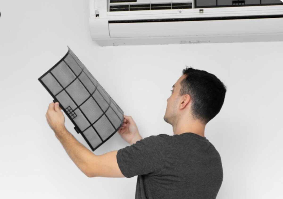 Homeowner cleaning air conditioner filter as part of basic AC maintenance